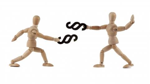 Zwei Holzfiguren bekämpfen sich mit großen Paragraphen Symbolen