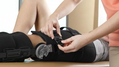 Foto: Einem Patienten wird eine Beinschiene für das sicherere Laufen angebracht