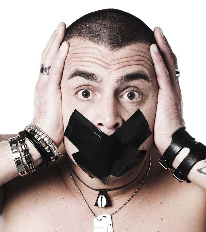 Ein Mann hält seinen Kopf und guckt schokiert. Sein Mund ist mit einem X zugeklebt.