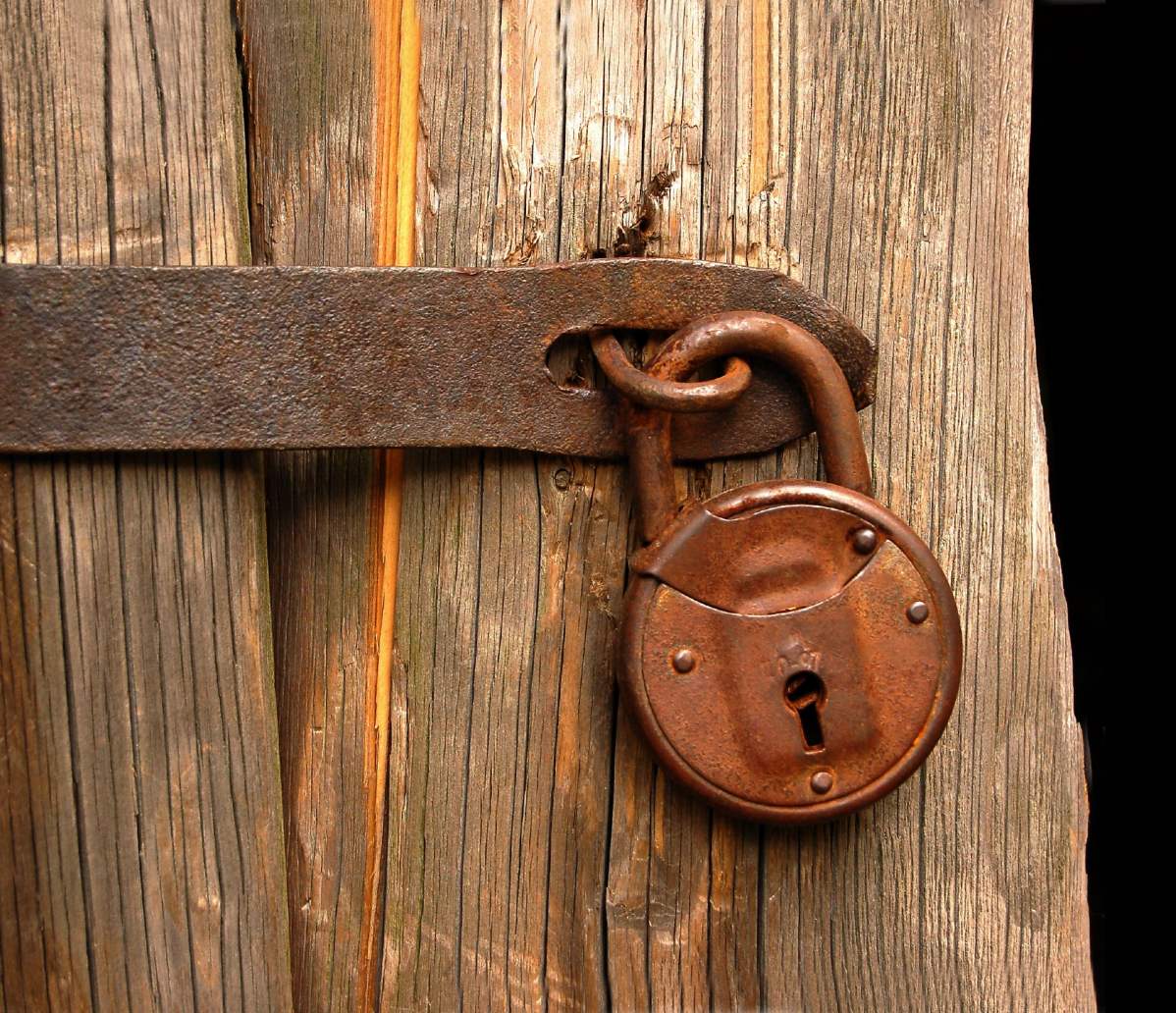 verilblichung des Locked-in Syndrom, ein Foto einer alten Tür mit einem Vorhängeschloss