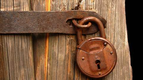 verilblichung des Locked-in Syndrom, ein Foto einer alten Tür mit einem Vorhängeschloss