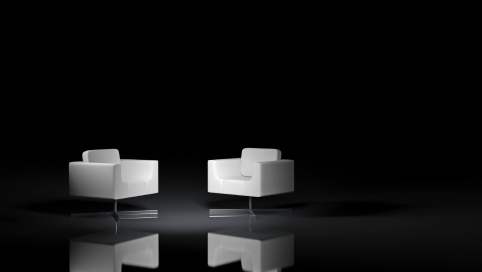 Zwei weiße Sessel stehen sich in einem dunklen Raum schräg gegenüber