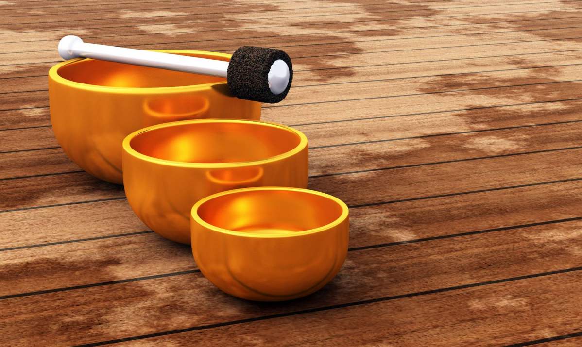 Foto: 3 unterschiedlich große Klangschalen aus einem glänzenden, orangfarbenen Metall stehen in einer Linie nebeneinander