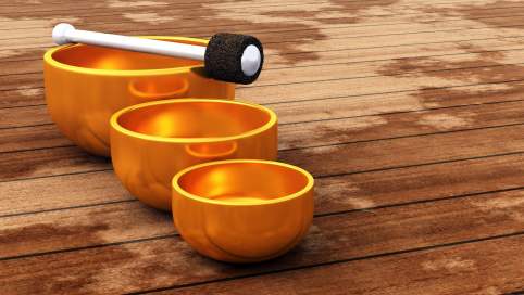 Foto: 3 unterschiedlich große Klangschalen aus einem glänzenden, orangfarbenen Metall stehen in einer Linie nebeneinander